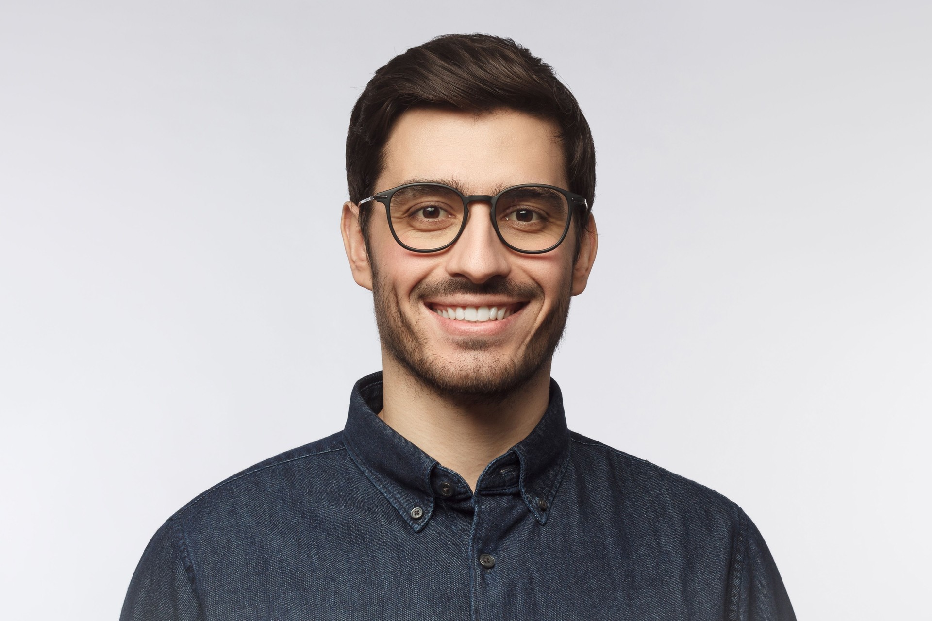 Headshot of cheerful handsome man with trendy haircut and eyeglasses isolated on gray background