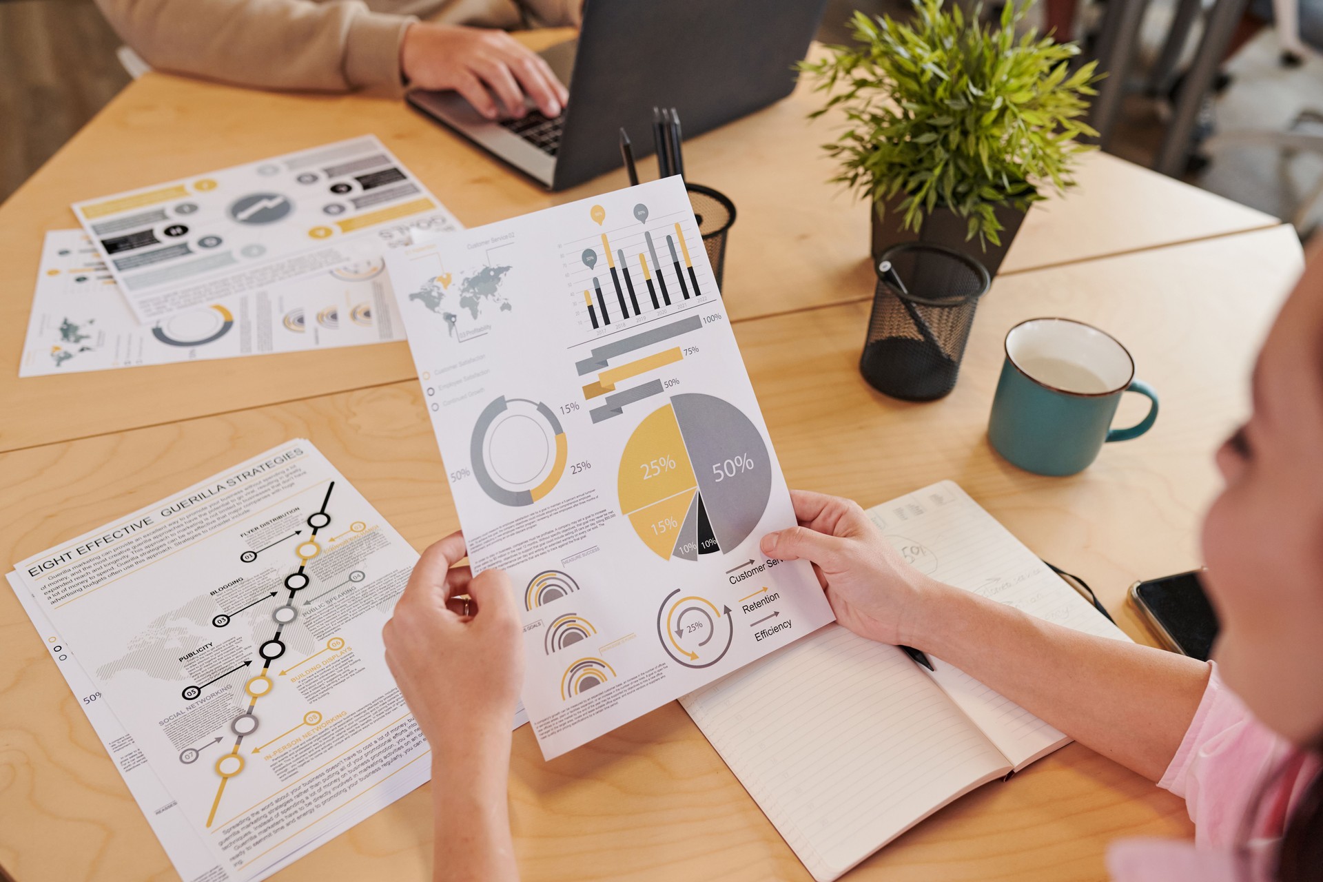 Close-up of unrecognizable woman analyzing statistical data while working with report in office